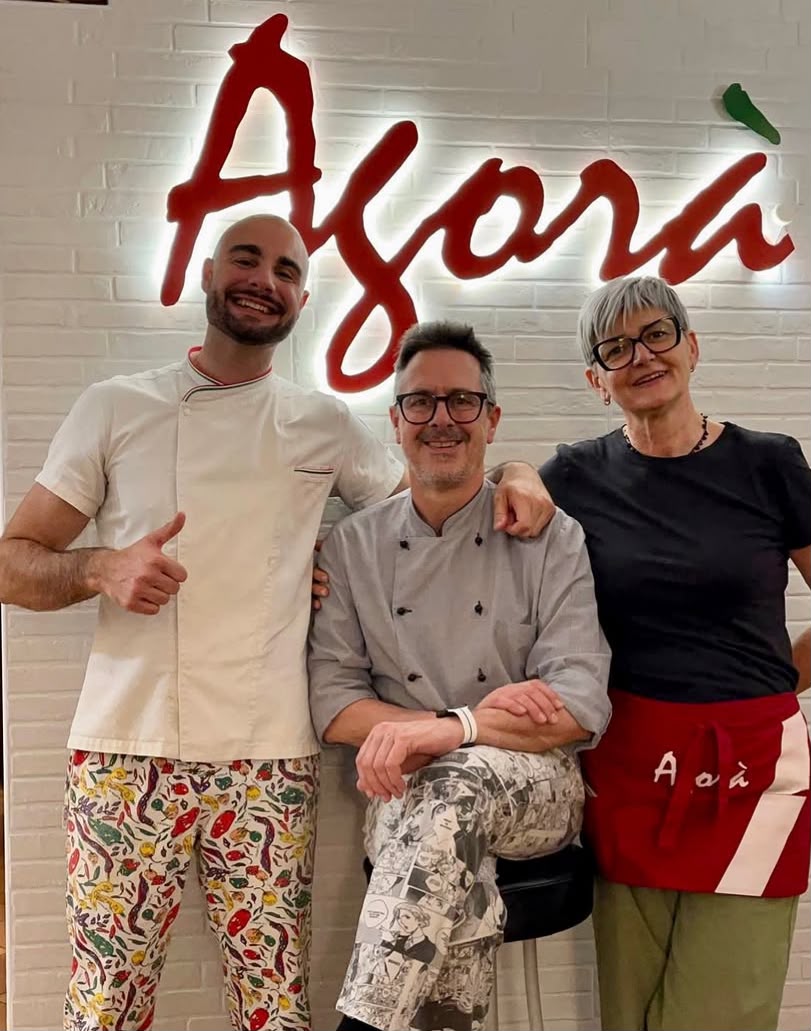 Lo staff di Pizzeria Agorà in sala, sotto l’insegna luminosa del locale