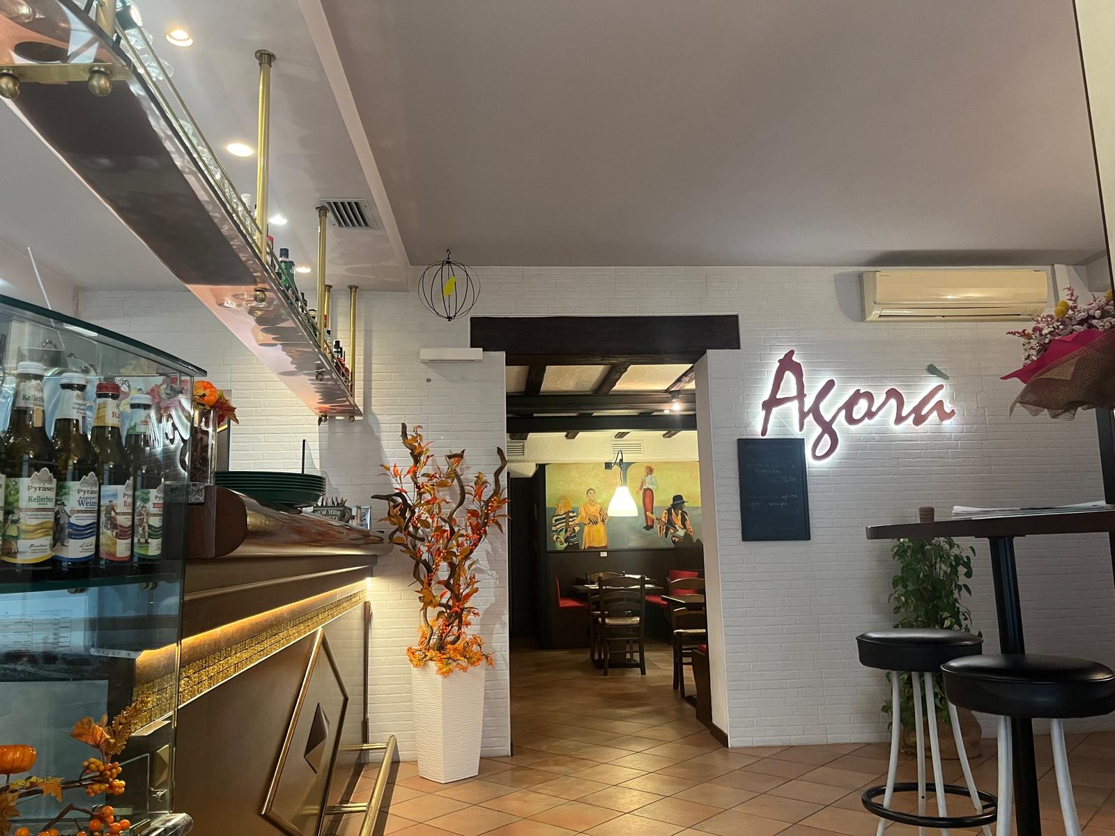 La sala di Pizzeria Agorà con l’insegna luminosa