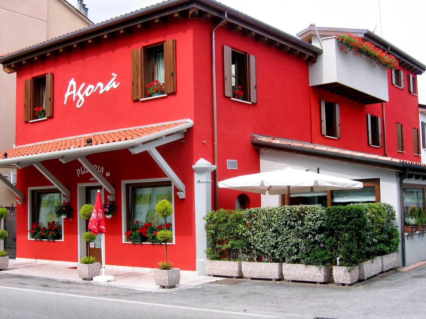 La facciata rossa di Pizzeria Agorà in Via Zermanese