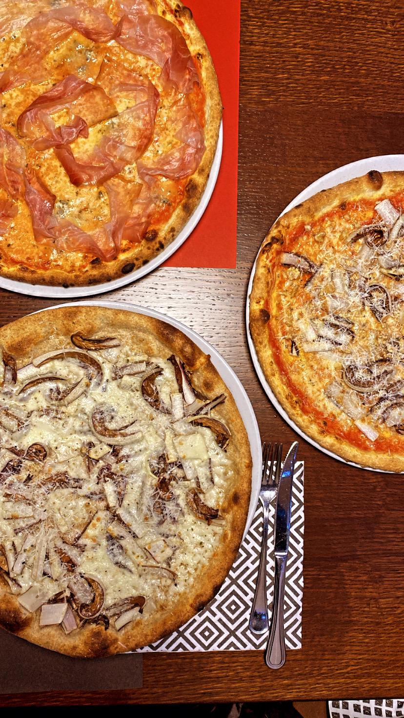 Tre pizze appena sfornate, servite in tavola da Pizzeria Agorà